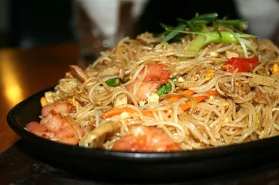 Noodles and vegetables in a black bowl