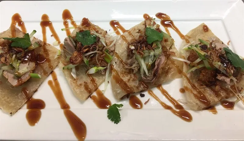 Roti with duck and dipping sauces on a white plate