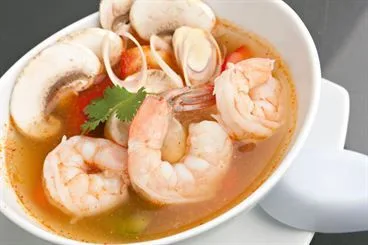 Tom yum prawn soup with dipping sauces on a wooden table
