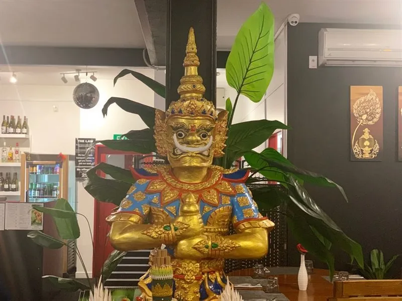 Thai giant statue beside plants inside Chai-Yo Restaurant